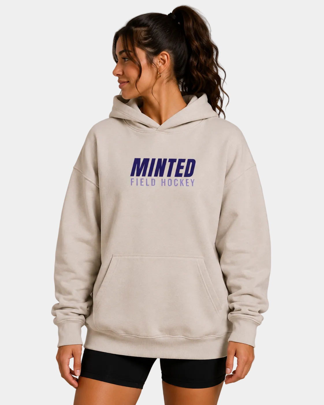 Woman wearing a beige hoodie with 'Minted Field Hockey' text on a gray background