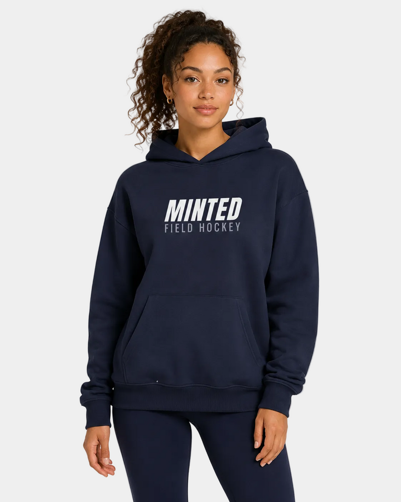 Person wearing a navy hoodie with 'Minted Field Hockey' text on a gray background
