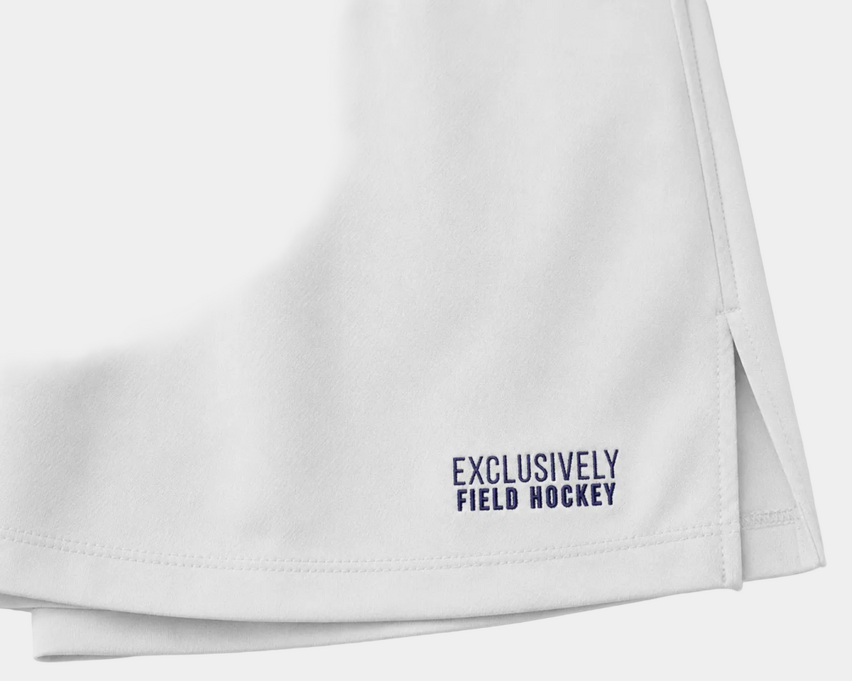 White skorts with 'Exclusively Field Hockey' text embroidered in blue