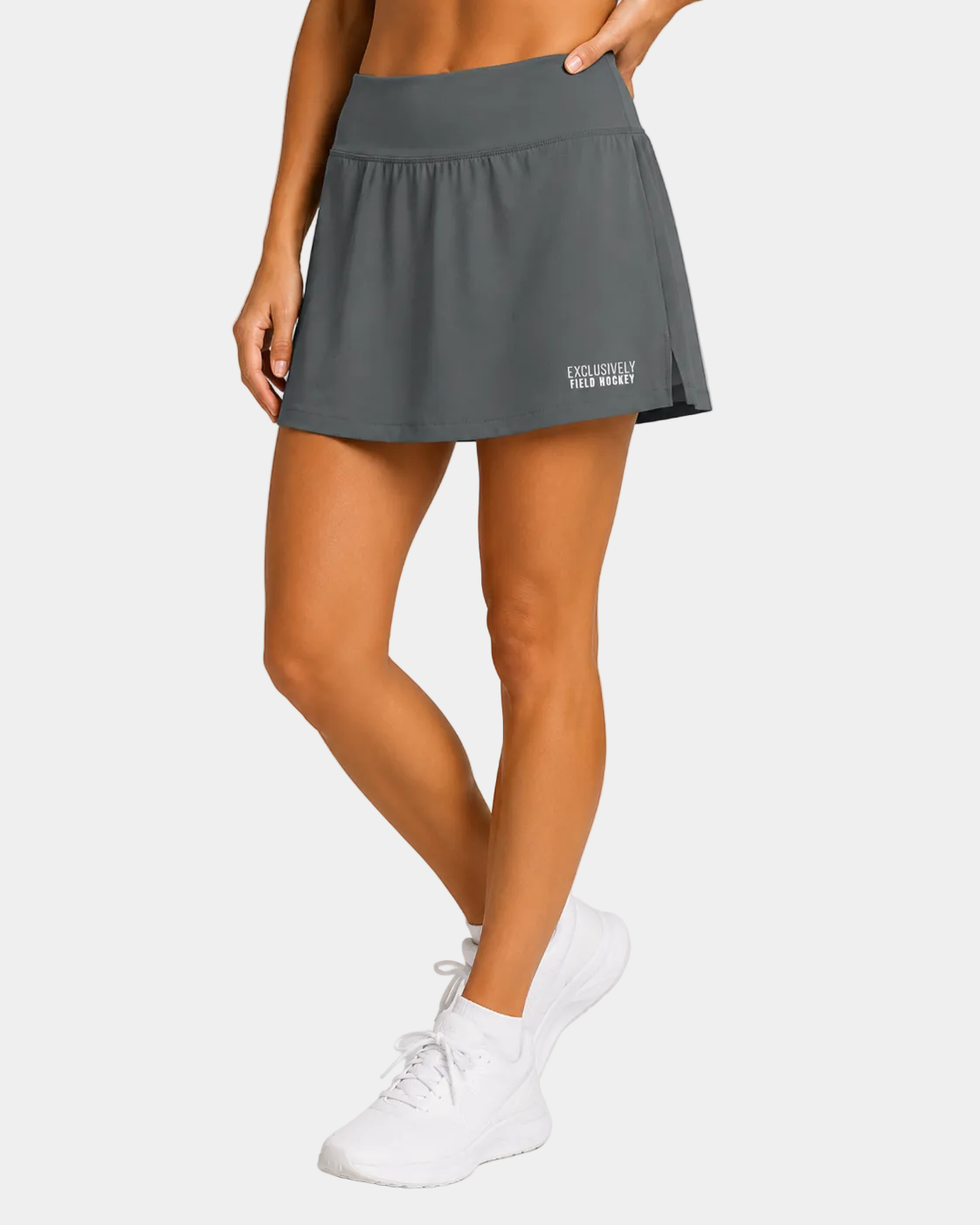 Field hockey player wearing grey skort with exclusively field hockey embroiderd in white.