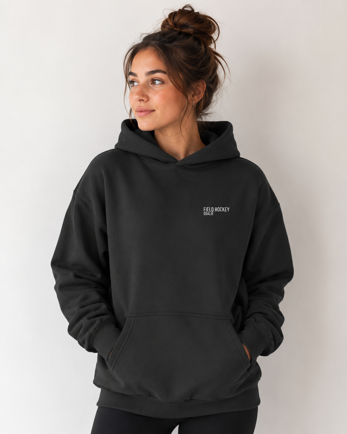 Girl wearing field hockey goalie hoodie with white embroidery text.