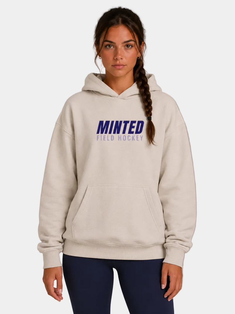 Woman wearing a beige hoodie with 'Minted Field Hockey' text on a gray background